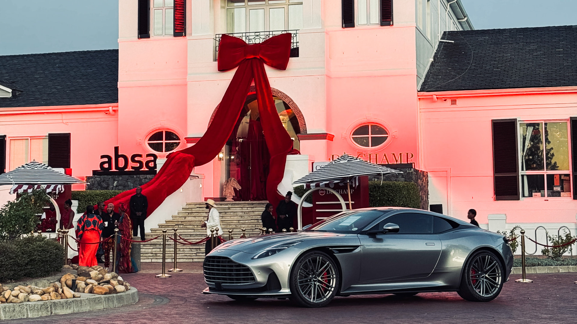 Silver DB12 in front of the ABSA du Champ pavilion draped with a red bow at Val de Vie