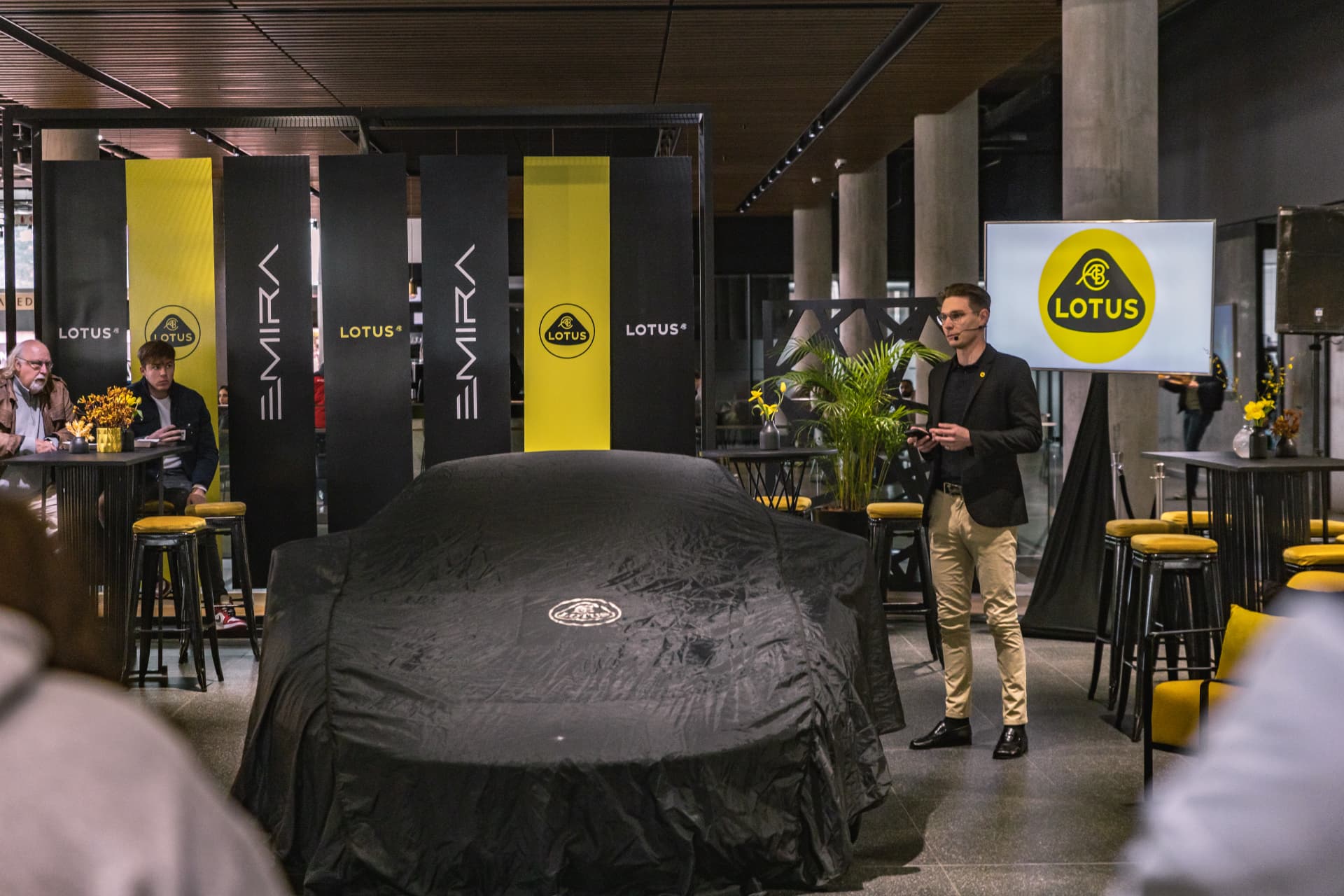 Presenter beside the covered Lotus Emira ahead of the South African launch unveiling