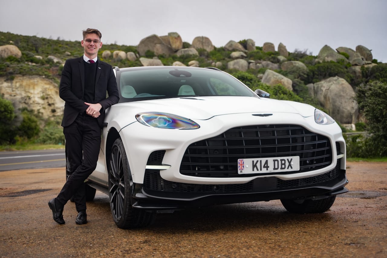 Man leaning against a white DBX 707 on a Cape mountain road
