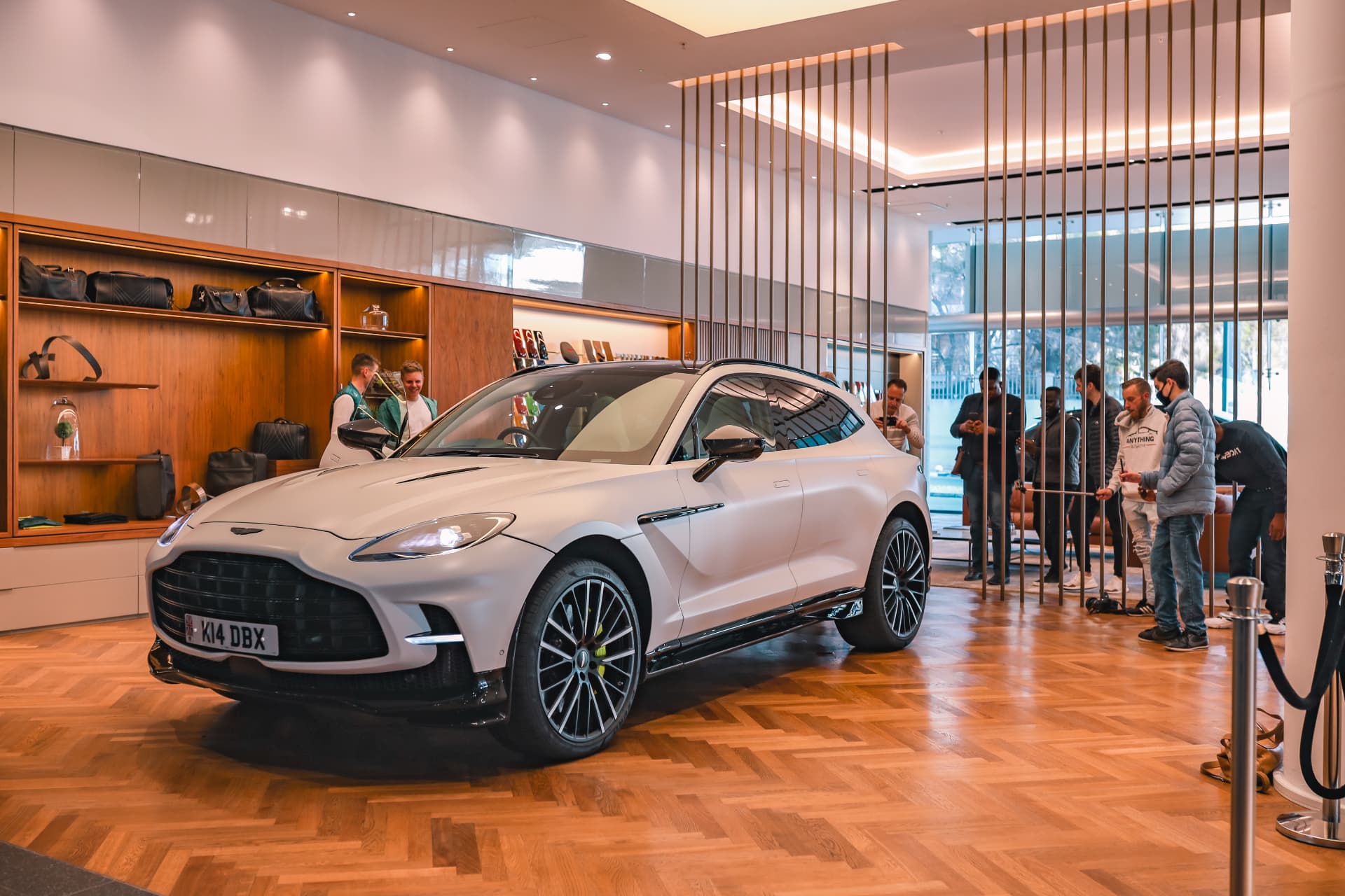 White Aston Martin DBX707 displayed inside a showroom with guests