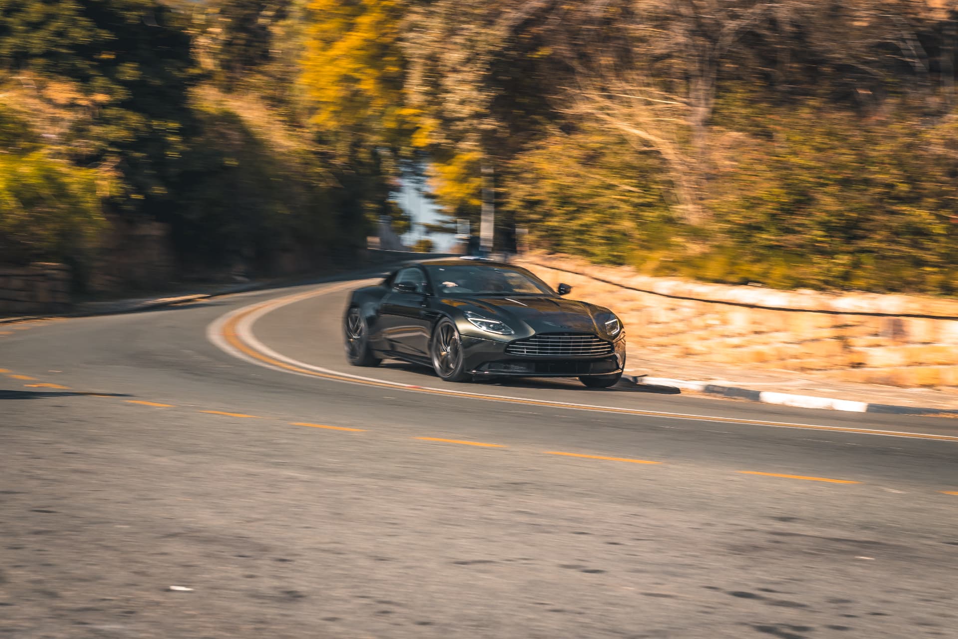 Dark green DB12 cornering on a mountain pass